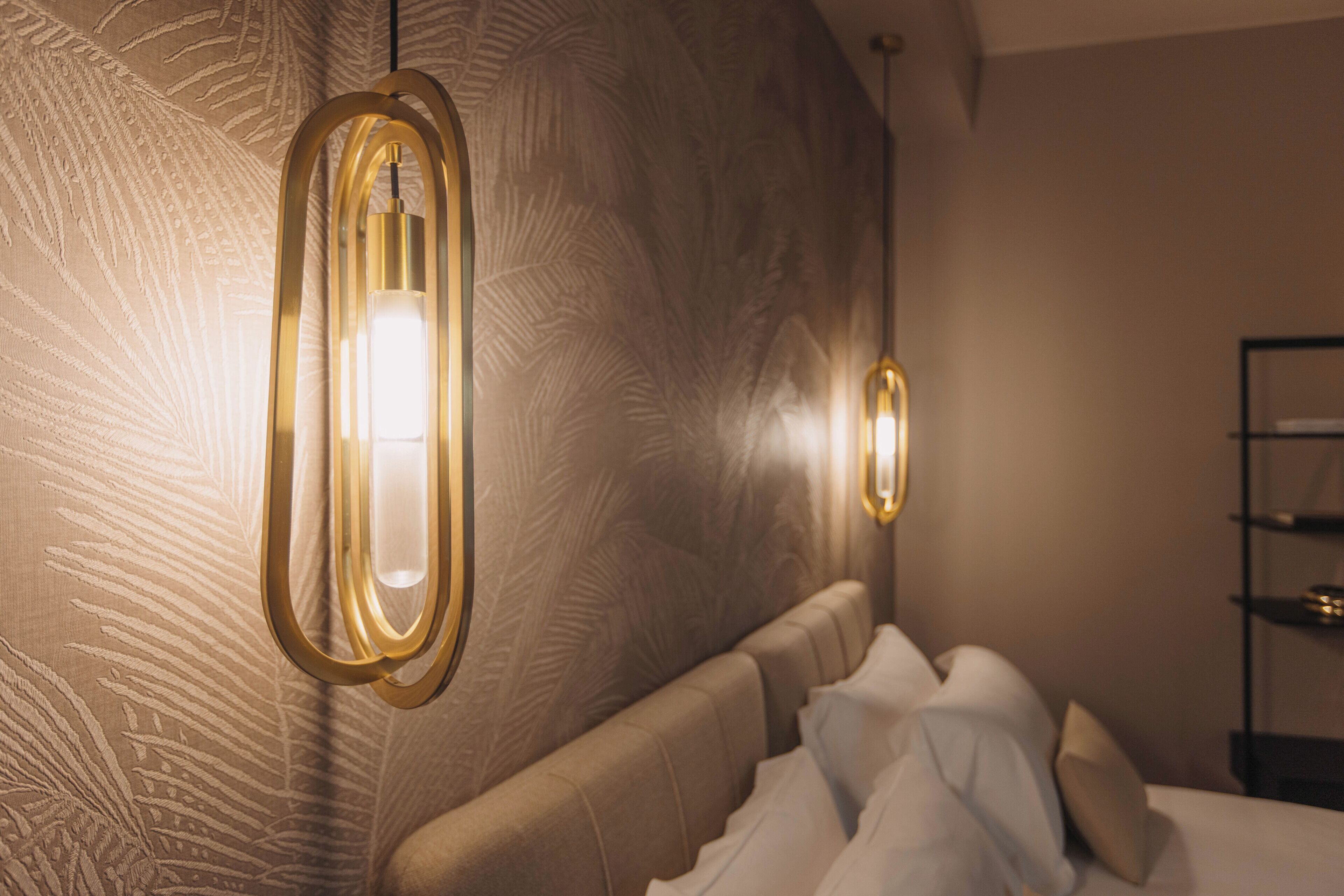 Ein Zimmer mit strukturierter Wand, einem Bett mit weißer Bettwäsche und zwei Wandleuchten.