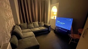 A living room with a sectional sofa, a flat-screen TV, and a lamp. - Glasgow City Escape - 2 Bedroom Apartment (Glasgow)