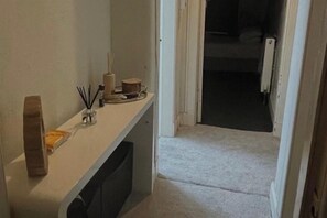 Ein Flur mit einer weißen Bank, einem kleinen Tisch mit Kerze und einer Tür zu einem weiteren Raum.