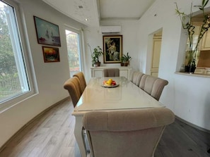 A dining area with a glass table, beige chairs, and a fruit bowl. - Modern Classic 2-Bedroom Apartment in Donja Lastva (Tivat)
