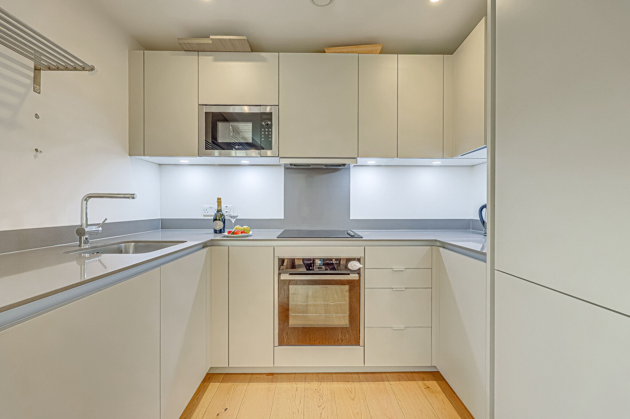 Een moderne keuken met een inbouwmagnetron, oven en spoelbak.