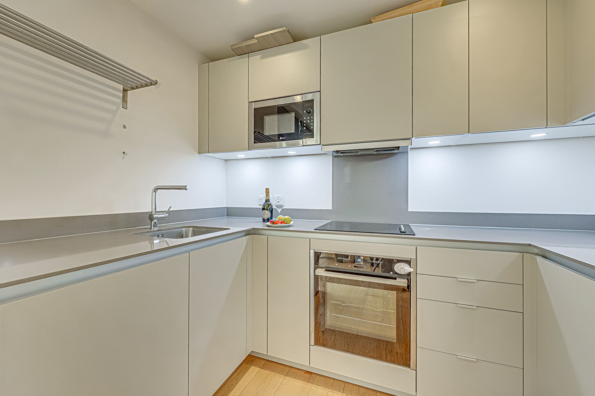 A modern kitchen with a built-in oven, a microwave, and a stainless steel sink.