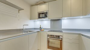 Una cocina moderna con horno empotrado, microondas y pileta de acero inoxidable.