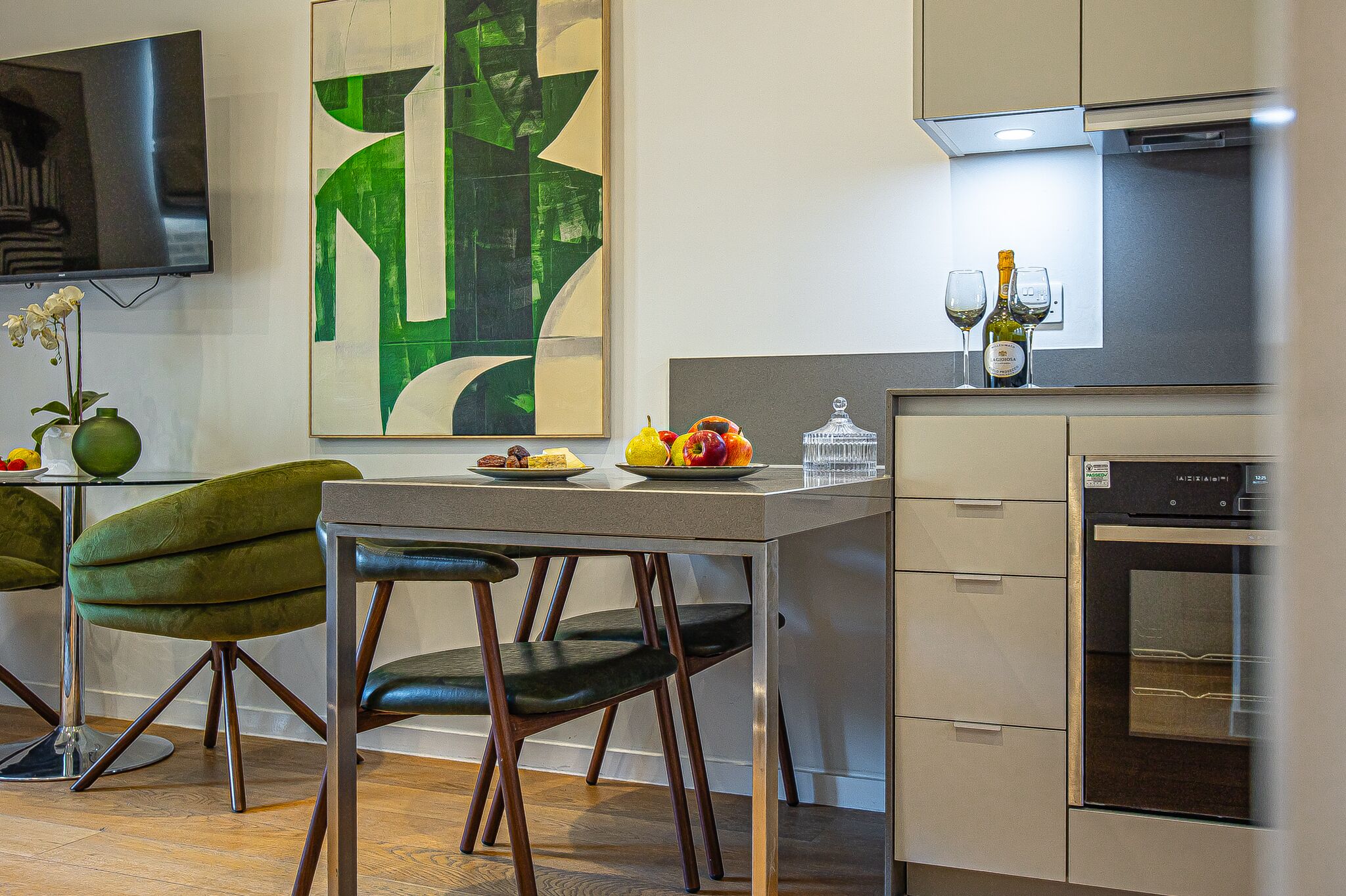 A modern kitchen with a dining table, chairs, and a refrigerator.