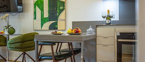 A modern kitchen with a dining table, chairs, and a refrigerator.