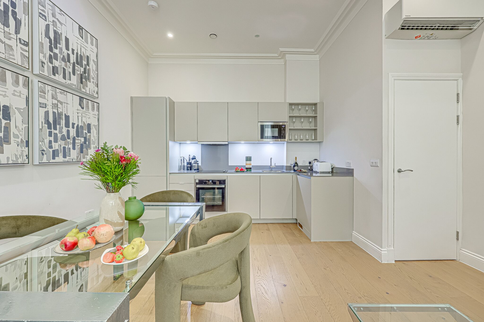 A modern kitchen with white cabinets, a dining table with chairs, and a vase with flowers.
