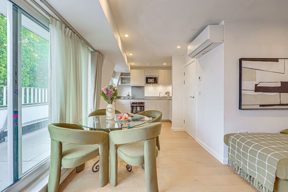 Una sala moderna con una mesa de comedor de vidrio, sillas verdes, un sofá y vistas a un balcón.