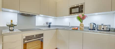 A modern kitchen with built-in appliances, a microwave, and a sink.