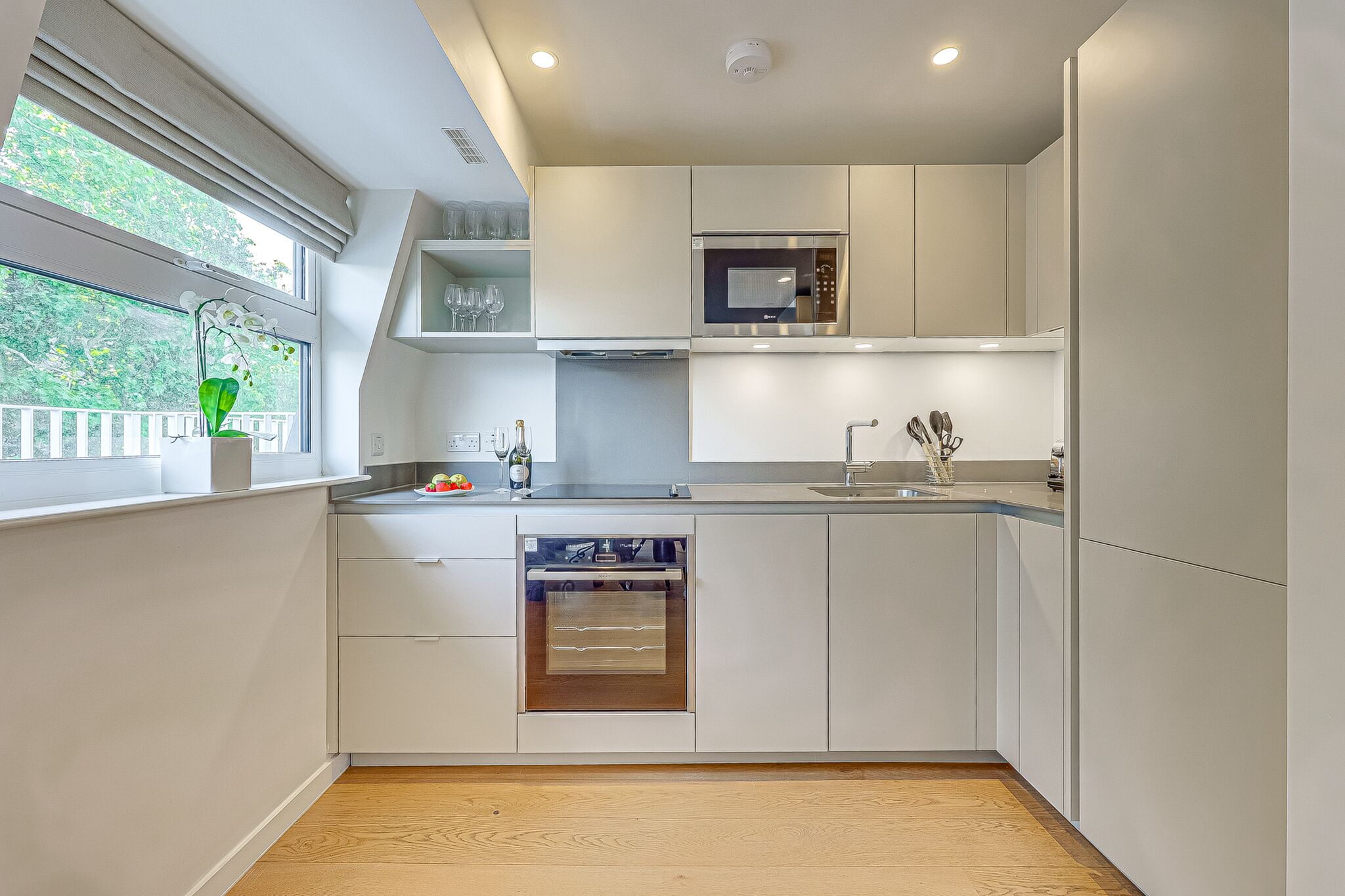 Una cucina moderna con elettrodomestici integrati, una finestra vista e un pavimento in legno.