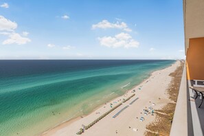 A beach view from a balcony with a clear sky, a sandy beach, and a row of umbrellas. - 2 Oceanfront Masters + Bunk, Sleeps 10, PCB (Panama City Beach)