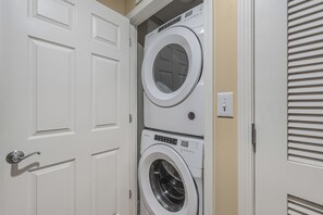 Lavandería con dos lavadoras apiladas, una puerta con manija y un enchufe de pared.