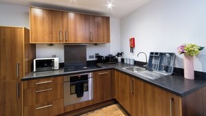 Een moderne keuken met houten kastjes, een inbouwoven, een magnetron en een spoelbak.