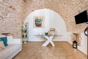 Uma sala de estar aconchegante com uma parede de pedra, uma mesa de vidro e uma pintura de um cacto.