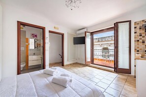 A hotel room with a bed, a bathroom, and a balcony with a view. - Helios Home (Conversano)