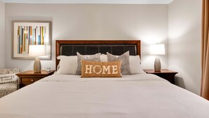 A neatly made bed with a pillow labeled 'HOME' in a hotel room. - Mesquite Breeze - A Ryson Property (Palm Springs)
