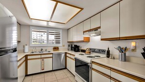 A kitchen with white cabinets, a stainless steel refrigerator, a stove, and a dishwasher. - Mesquite Breeze - A Ryson Property (Palm Springs)