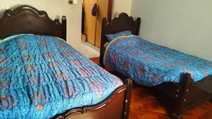 Dos camas de madera con cabeceras y pieceras a juego, un armario de madera y una puerta con una toalla colgada.