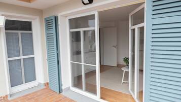 A room with a sliding glass door, a small table with a plant, and a white door leading to another room.