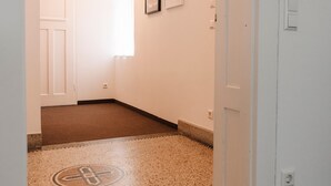 A hallway with a carpeted floor, a door, a light switch, and a thermostat on the wall. - Apartment 'Ferienwohnung Ambiente Am Federsee' with Wi-Fi (Bad Buchau)