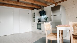 Une cuisine moderne avec des meubles blancs, un four encastré, un réfrigérateur en acier inoxydable et un plafond en bois.