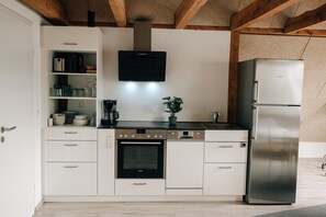 A modern kitchen with white cabinetry, a Bosch oven, a Siemens refrigerator, and a black wall-mounted coffee maker.