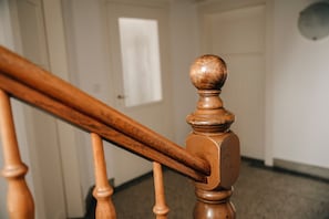 A wooden staircase with a rounded baluster and a door in the background.