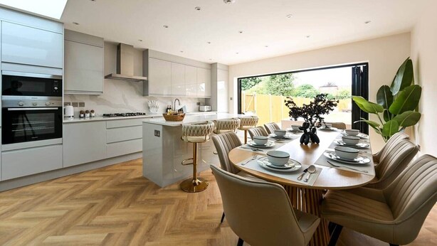 A modern kitchen with built-in appliances, a dining area with a central island, and a view of the outdoors. - 5BR Family Home | Garden | AC | Near Wembley (Greenford)
