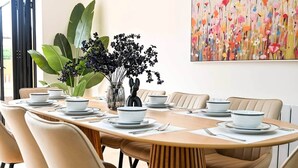 A dining area with a round table set for six, surrounded by six chairs. - 5BR Family Home | Garden | AC | Near Wembley (Greenford)