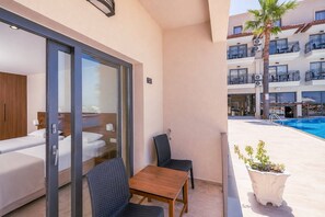 Quarto de hotel com varanda, piscina e vista para a fachada do edifício.