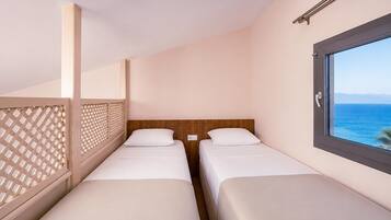 A twin bedroom with two beds, a window with a view of the sea, and a balcony with a lattice screen.