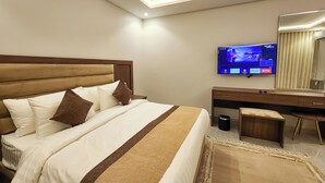 Una habitación de hotel con cama, televisión, escritorio y espejo.