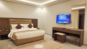 Una habitación de hotel moderna con una cama grande, televisión, escritorio y espejo.