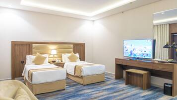 Habitación de hotel con dos camas, un escritorio, un televisor y un cesto de basura.