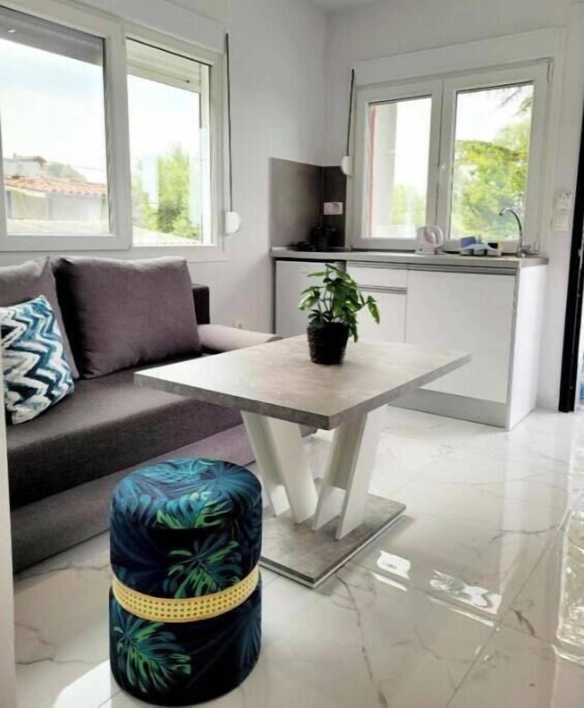 A modern kitchen with a dining area, a sofa, and a small round ottoman.