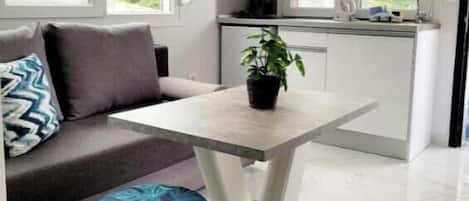 A modern kitchen with a dining area, a sofa, and a small round ottoman.