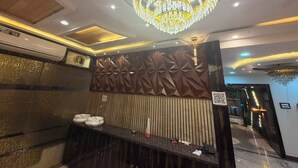 Un moderno vestíbulo de hotel con una gran lámpara de araña, una recepción y un panel decorativo en la pared.
