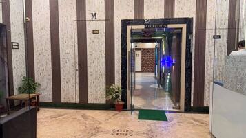 A reception area with a marble floor, vertical striped wallpaper, and a reception desk.