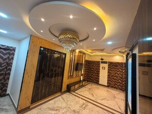Un vestíbul d'hotel amb una làmpada sospesa moderna, una recepció i una paret amb un disseny original.