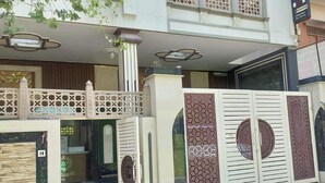 Un edificio residencial de varios pisos con entrada porticada, paneles decorativos y un balcón visible.