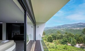 Ein moderner Balkon mit Glasgeländer und Blick auf eine gebirgige Landschaft.