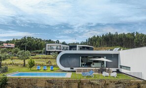 Una casa moderna amb piscina, mobiliari exterior i vistes a un bosc.