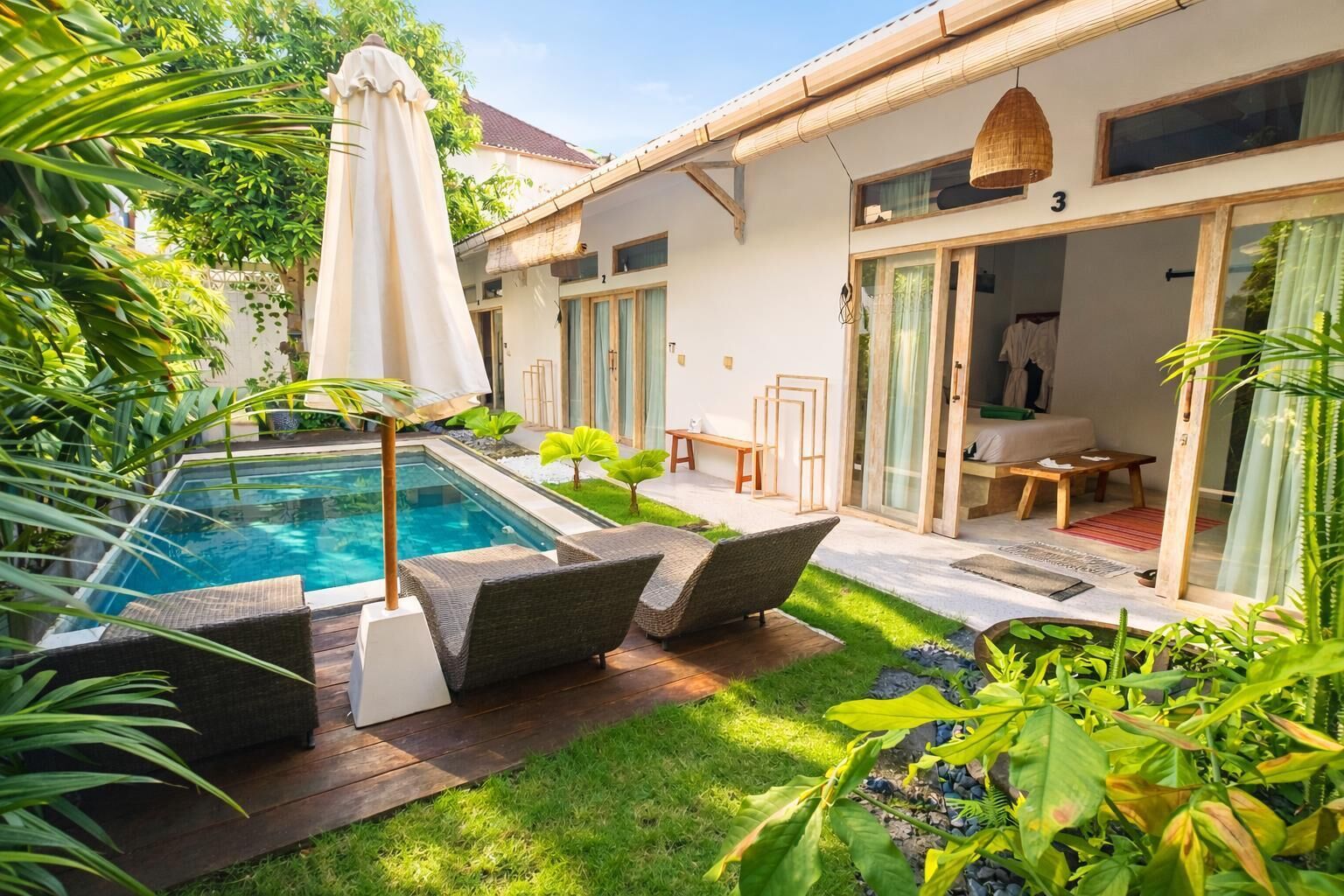 A poolside area with lounge chairs, a small pool, and a building with a glass door.