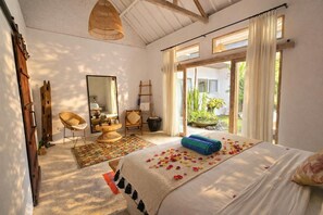Une chambre à coucher avec un lit, une chaise, un miroir, une fenêtre et une vue sur l’extérieur.
