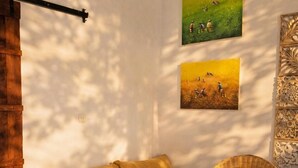 A cozy room with a wooden bed, a wicker chair, and two paintings on the wall. - Luxury 3-BR Villa, Canggu Berawa , Private Pool (Kec. Kuta Utara)