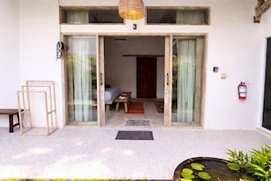 A building entrance with a number '3' above the door, a fire extinguisher on the wall, and a small outdoor seating area with a table and chairs. - Luxury 3-BR Villa, Canggu Berawa , Private Pool (Kec. Kuta Utara)