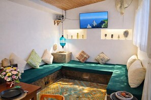 A cozy room with a green cushioned seating area, a flat-screen TV mounted above, and a patterned floor. - Luxury 3-BR Villa, Canggu Berawa , Private Pool (Kec. Kuta Utara)