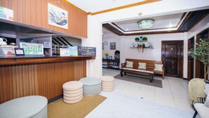 Zona de recepción con mostrador de madera, un banco y un sofá.