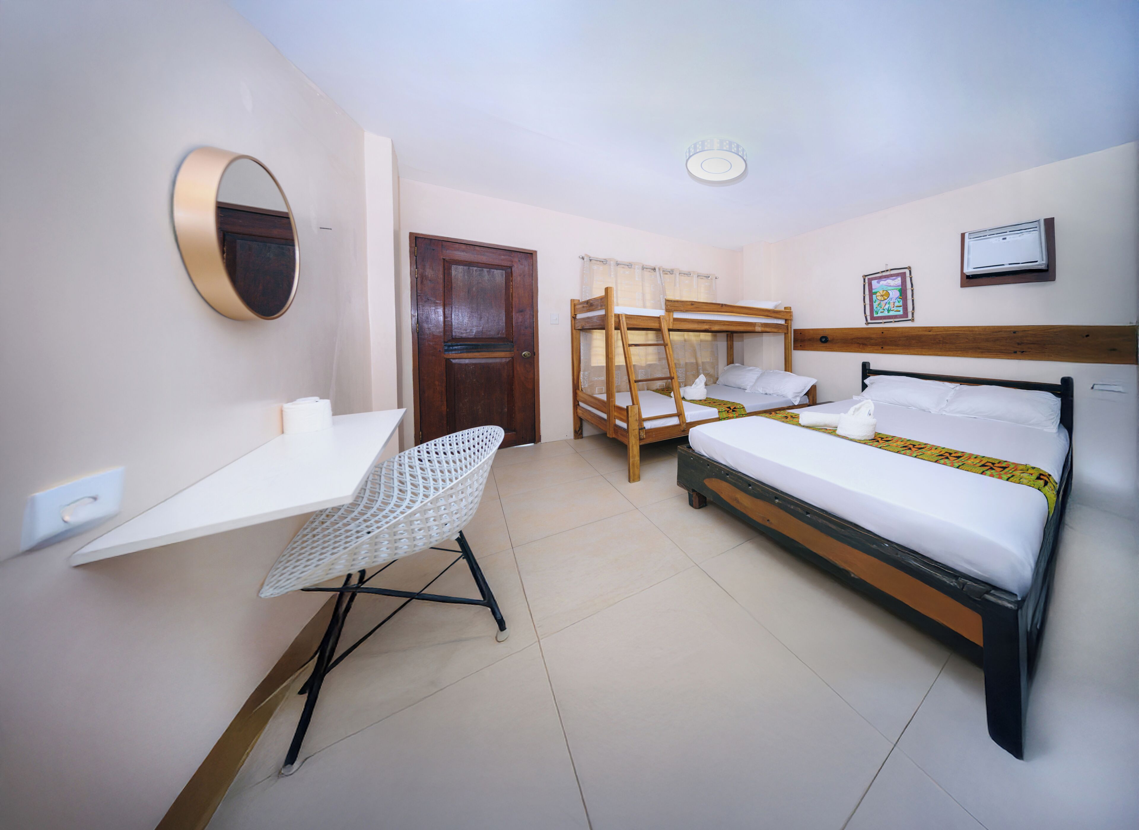 A room with bunk beds, a desk, a chair, a mirror, and a door.