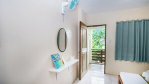 Un baño con lavamanos blanco, espejo, toallero y cortina de ducha.