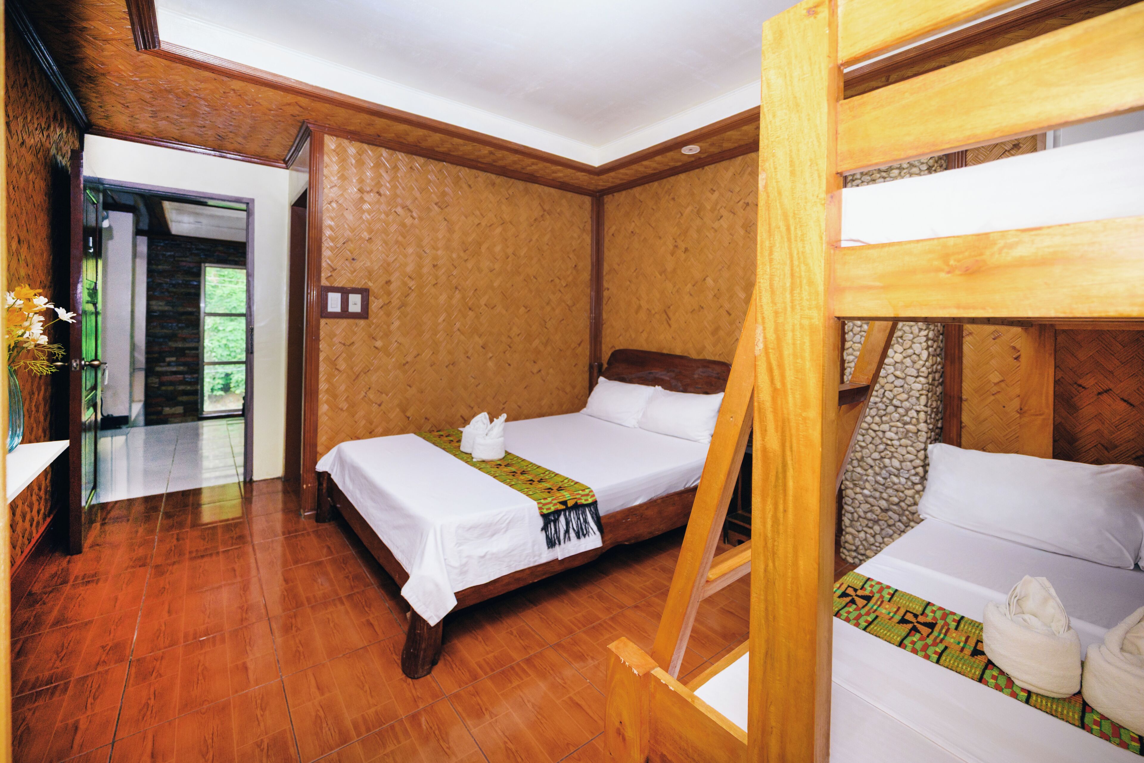 A room with a wooden bed, a wooden bunk bed, and a wooden floor.